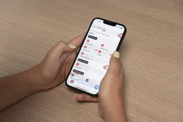 Application Déplacements professionnels DailyApps : main tenant un téléphone